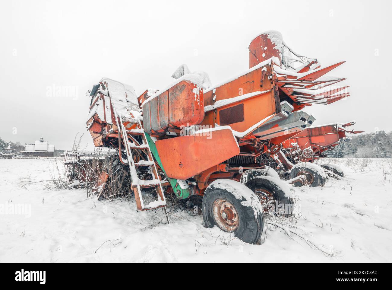 Rot gebrochene gefrorene Mähdrescher auf einem schneebedeckten Feld. Alte kaputte Landmaschinen im Schnee. Rückansicht Stockfoto