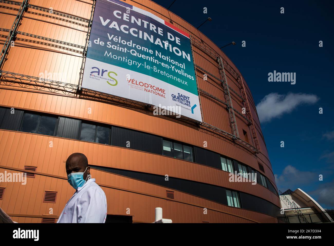 ©Christophe Petit Tesson/MAXPPP - 26/03/2021 ; MONTIGNY LE BRETONNEUX ; FRANKREICH - UN Agent d'accueil devant le velodrome de Saint Quentin transforme en Centre de Vaccination pour les personne age de + 55 ans ou atteint de comorbidites. Blick auf das Impfzentrum Covid-19, das im nationalen Velodrom in Saint-Quentin-en-Yvelines in der Nähe von Paris eingerichtet wurde. Frankreich kündigte am 23. März an, seine Strategie zu ändern und auf eine Massenimpfung zu drängen, die aufgrund der Zunahme von Coronavirus-Infektionen in Nordfrankreich und der Region Paris verursacht wurde. Stockfoto