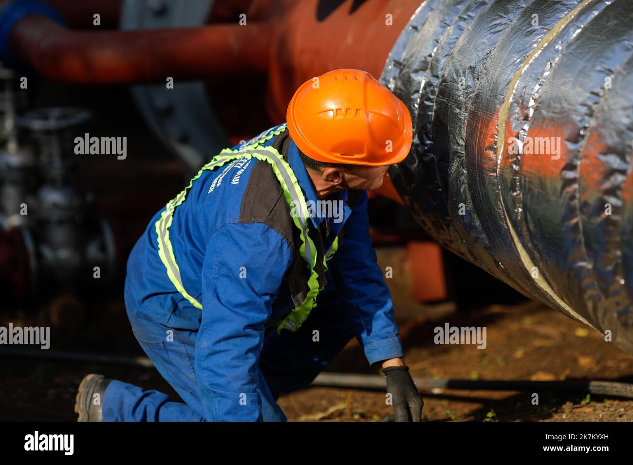 Bukarest, Rumänien - 13. Oktober 2022: Arbeiter verwendet Glaswolle, um eine Heißwasser-Metallleitung thermisch zu isolieren. Stockfoto