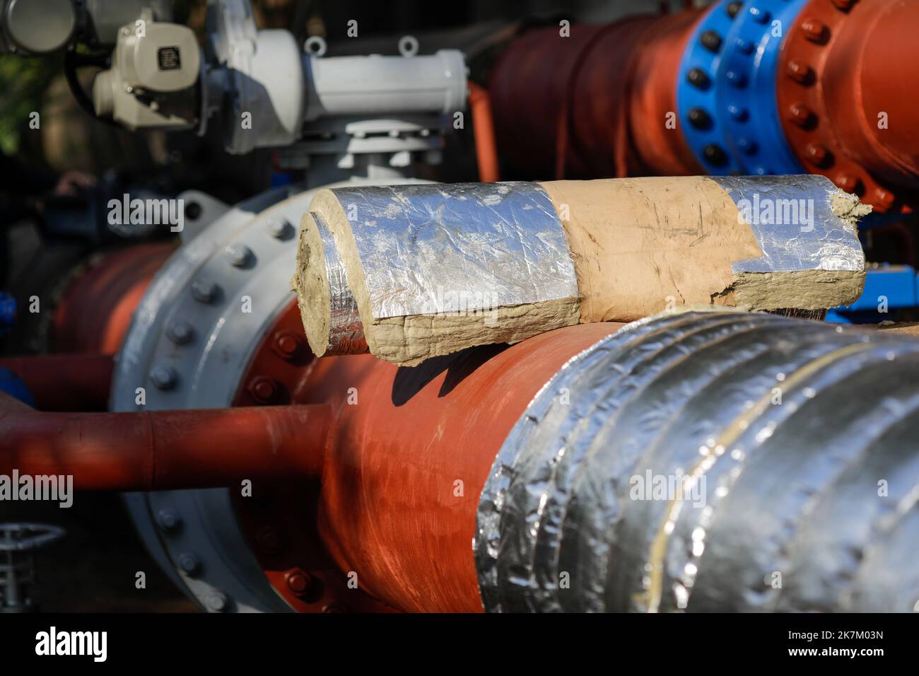 Details zur geringen Schärfentiefe (selektiver Fokus) mit industrieller Glaswolle, die zur thermischen Isolierung einer Heißwasser-Metallleitung verwendet wird. Stockfoto