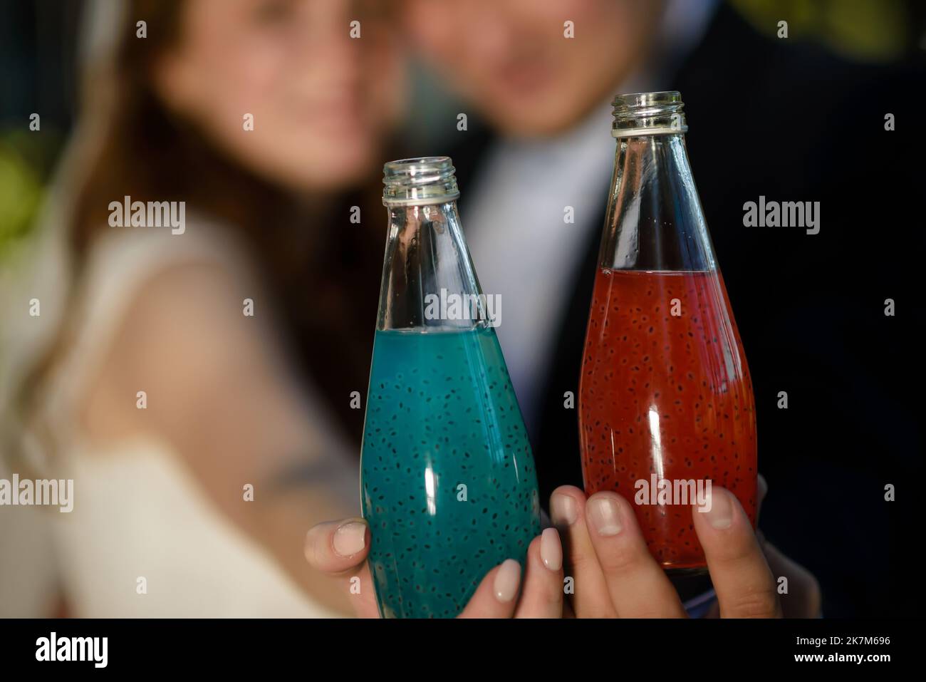 Nahaufnahme von drei Glasflaschen mit kalten Orangensaft, rotem und grünem Saft, Cocktailgetränken mit Chiasamen auf zerkleinertem Eis im Einzelhandel, Seitenansicht in niedriger Winkel Stockfoto