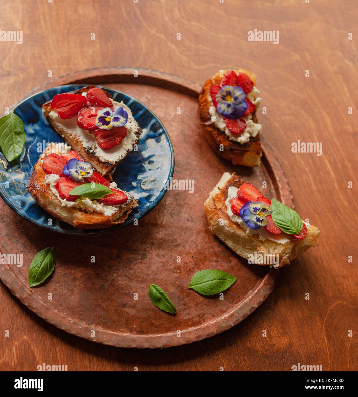 Strawberry Toast Brioche mit Frischkäse mit Blumen verziert und Basilikum flach legen aus der Nähe Stockfoto