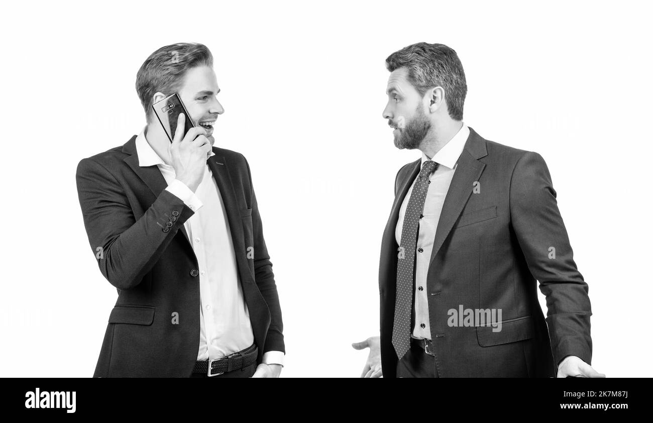 Wütender Chef streitet mit lächelndem Mitarbeiter, der am Telefon spricht, isoliert auf Weiß, Konflikt Stockfoto