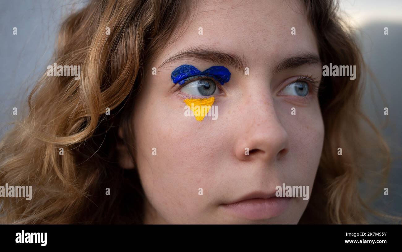 Nahaufnahme des weiblichen Gesichts mit gelb-blauem Herz um das Auge. Stoppt die russische Aggression in der Ukraine. Hoffnung und Glaube, Angst, Hilflosigkeit. Ansprechen Stockfoto