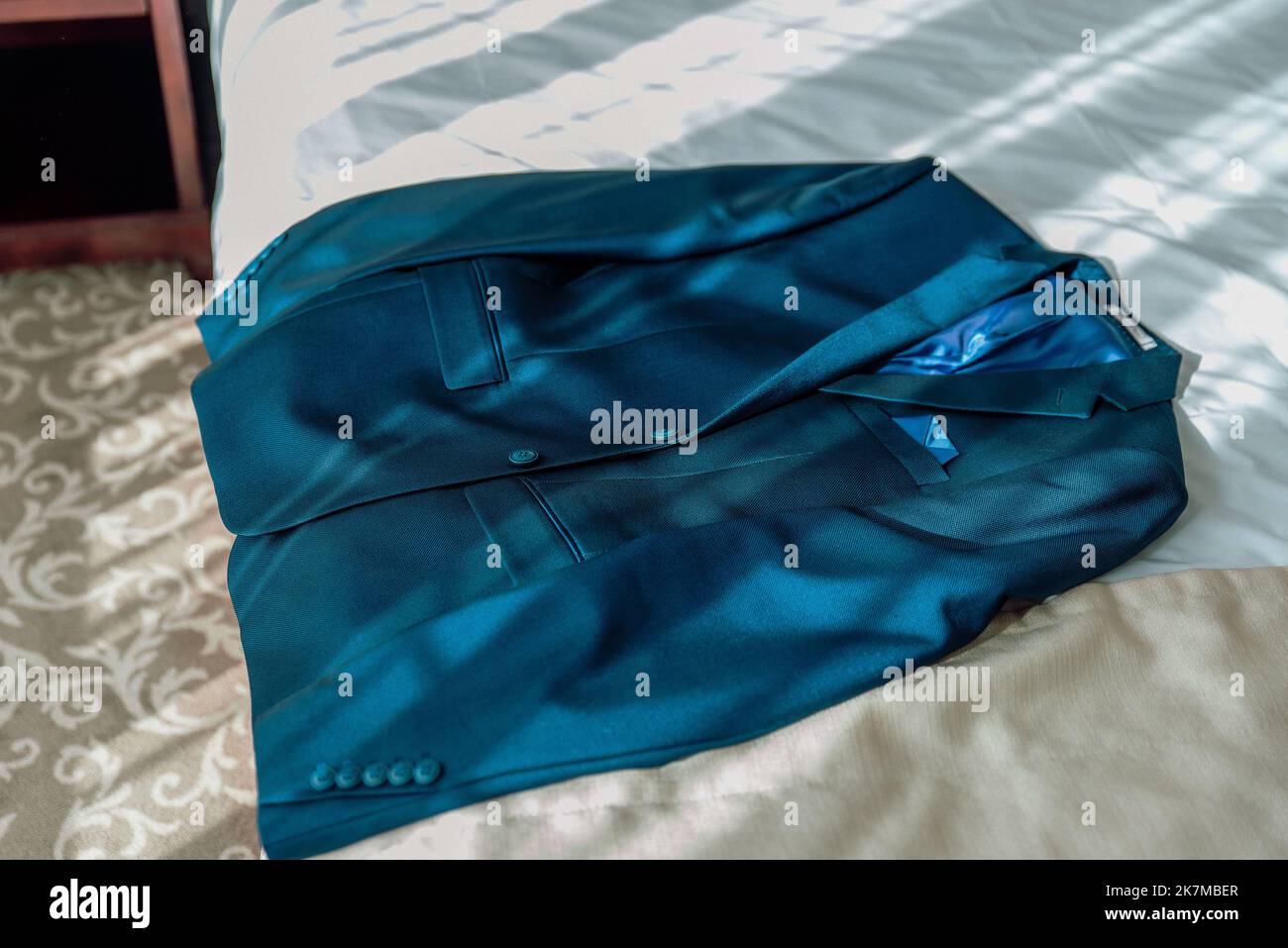 Stilvoller, eleganter Hochzeitsanzug mit Aufhängung im Hotelapartment. Hochzeitszubehör für den Bräutigam. Stockfoto