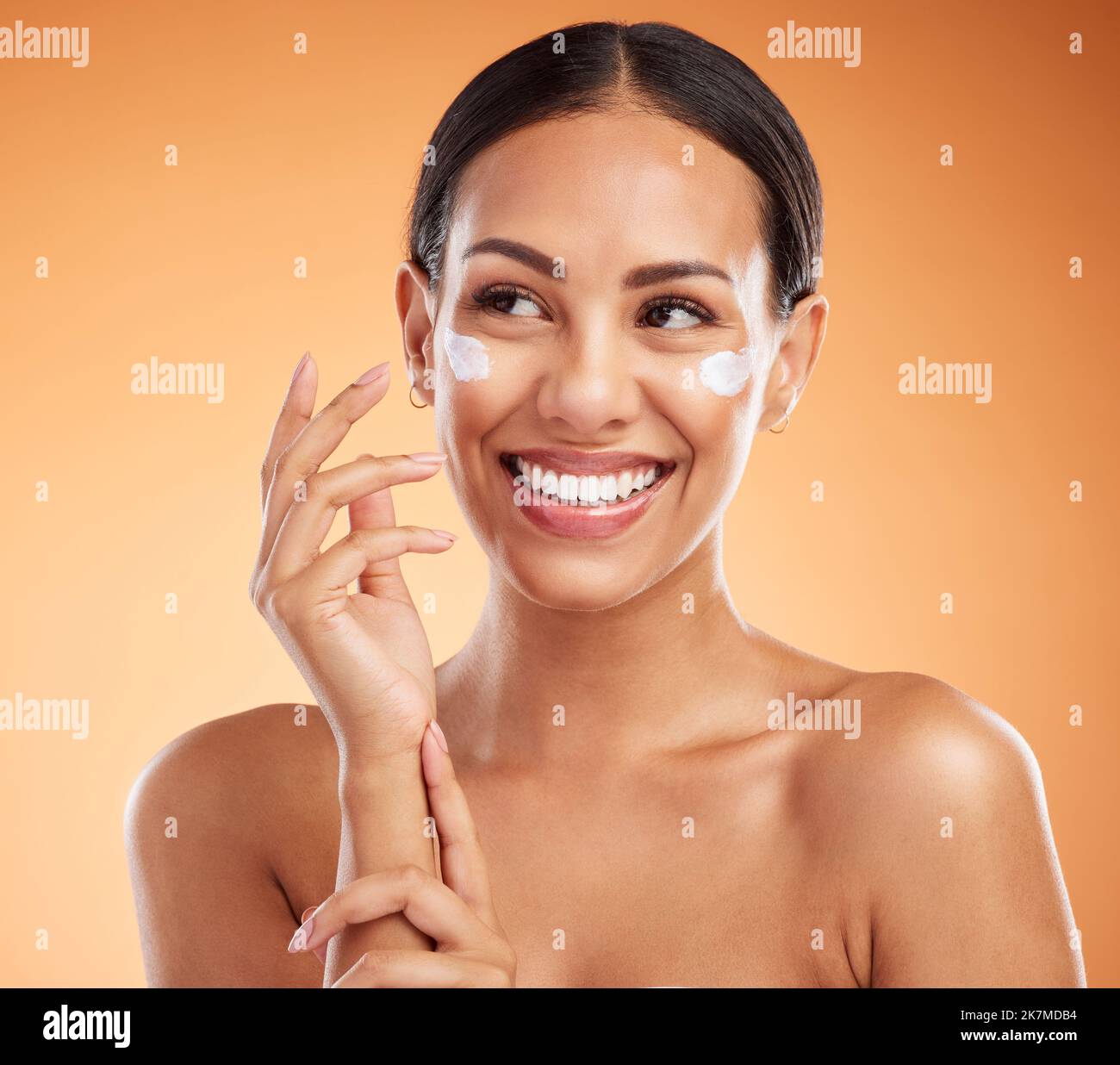 Schönheit, Hautpflege und Gesichtscreme auf Frau mit Lächeln, zufrieden mit Produkt für die Haut vor braunem Studio-Hintergrund. Happy Latino Modell mit Make-up Stockfoto