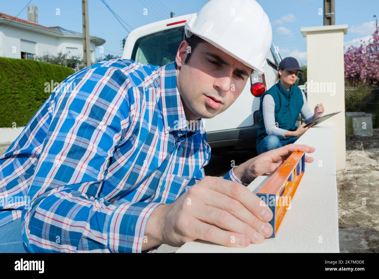 Arbeiter, der den Füllstand der niedrigen Wand mit der Wasserwaage überprüft Stockfoto