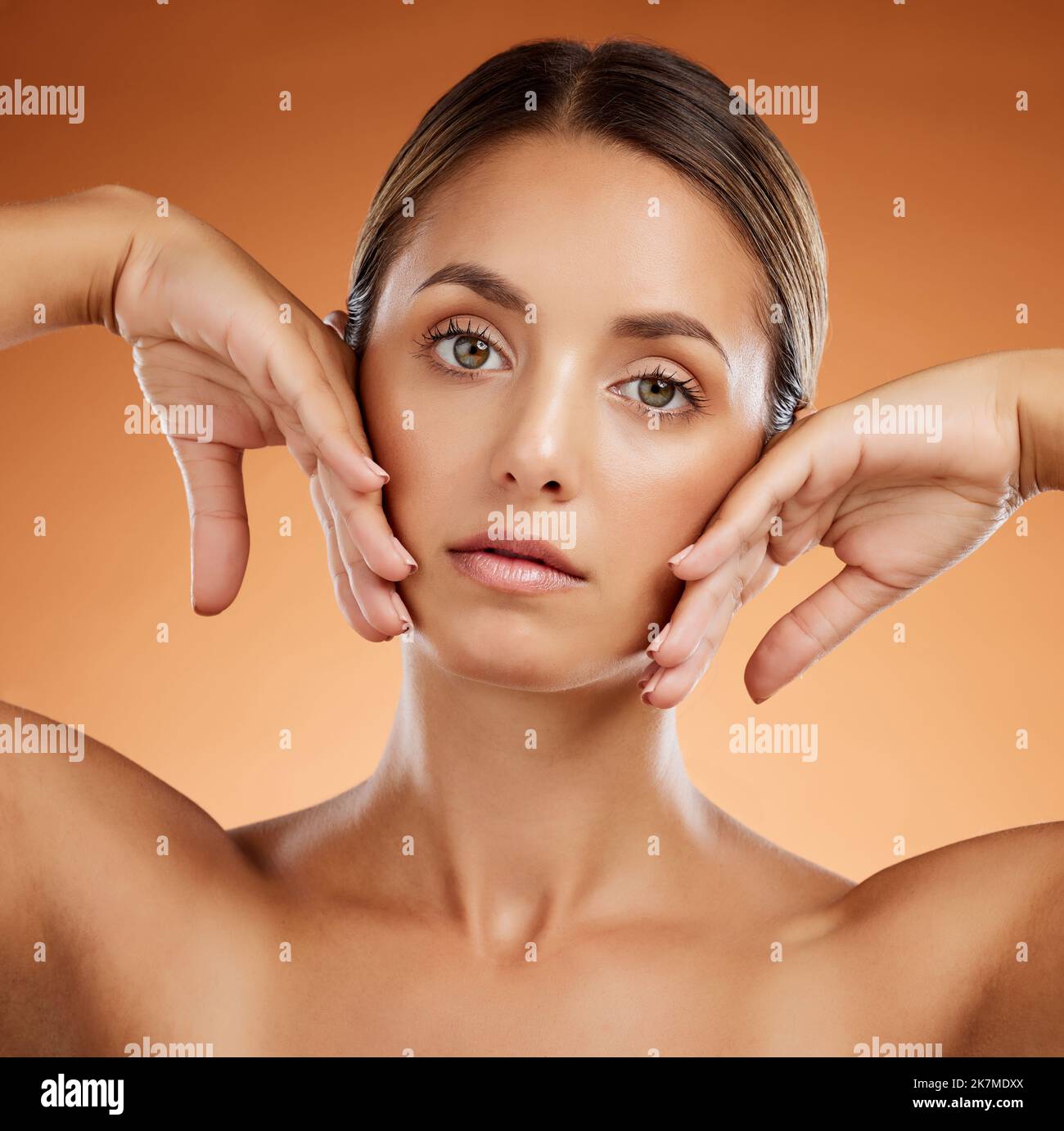 Hautpflege, Schönheit und Frau mit Glanz im Gesicht vor einem orangen Studiohintergrund. Porträt eines jungen, gesunden und kosmetischen Modells mit Körperschminke Stockfoto
