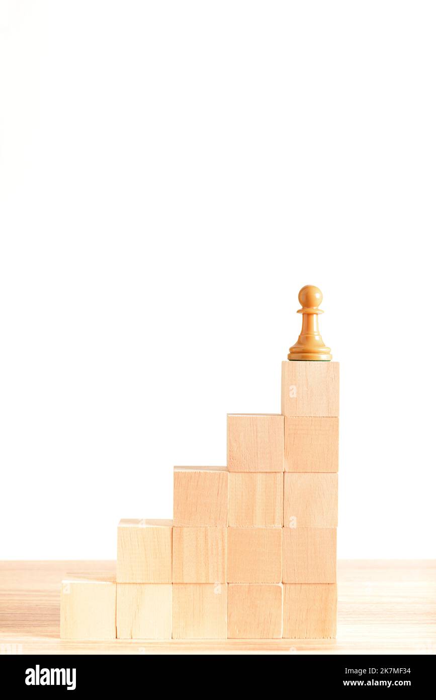 Schachfigur an der Spitze einer Treppe aus Holzblöcken, mit weißem Hintergrund. Konzept der Selbstverbesserung, Führung und Erfolg. Platz für CO Stockfoto