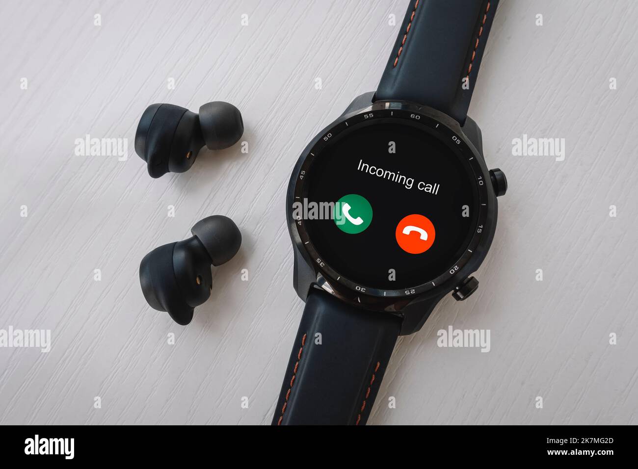 Eingehende Anrufe auf einer modernen Smart Watch. Schwarze Smart Watch und kabellose Kopfhörer auf weißem Hintergrund. Stockfoto