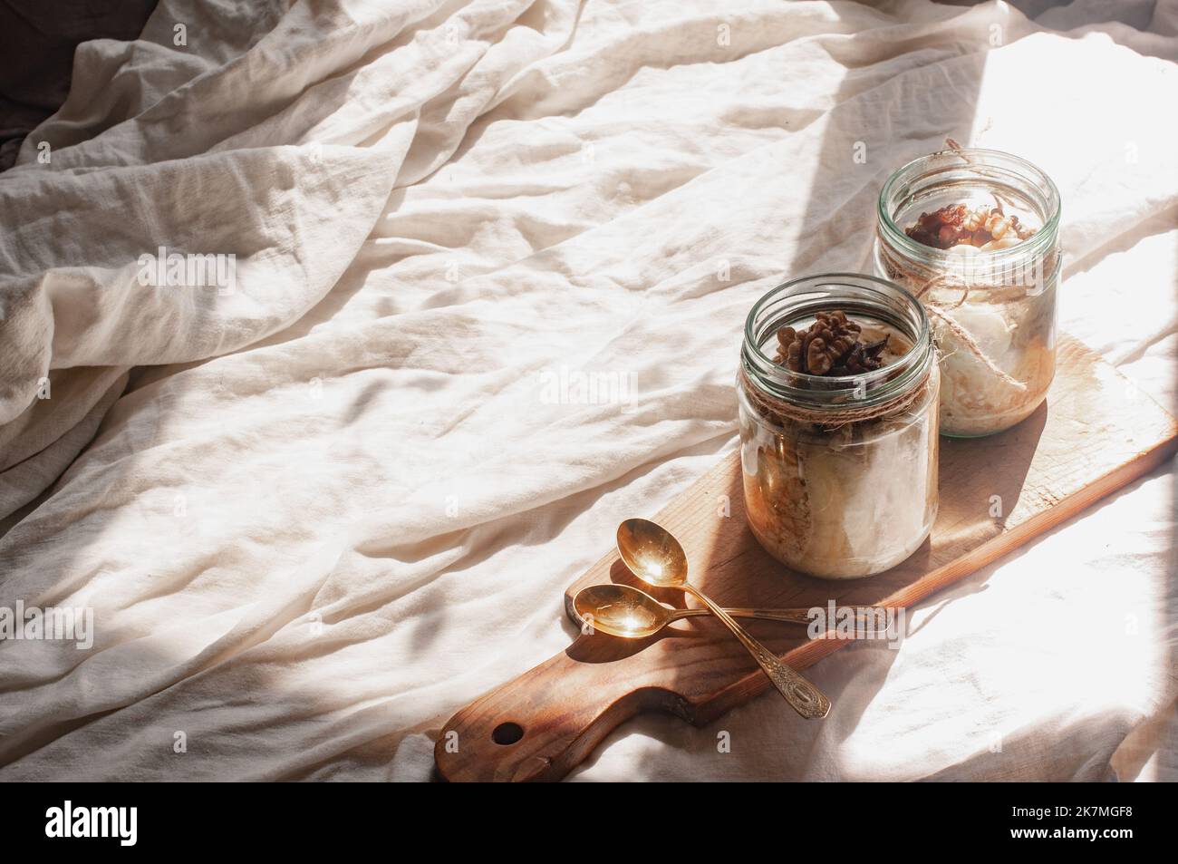 Köstlich über Nacht kein Koch vegane rohe rustikale Haferflocken in einem Glas mit Banane und Datteln auf minimalistischem sonnigen schönen neutralen beigen Hintergrund Stockfoto