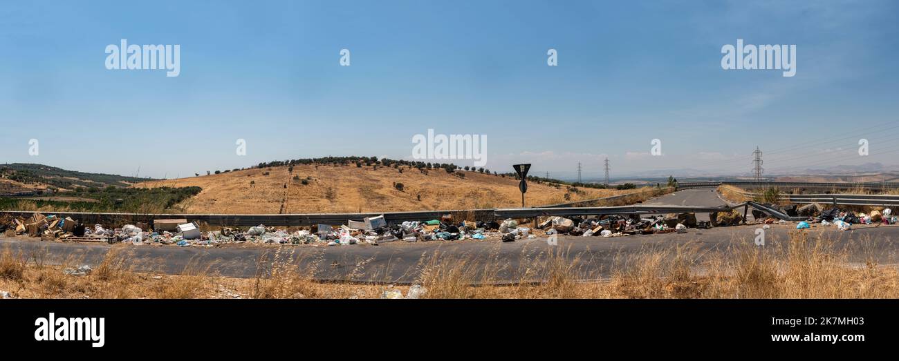 Ein Panoramablick auf die sizilianische Landschaft mit Müll, der am Straßenrand gedumpt wird, ein häufiger Anblick über Sizilien in ländlichen Gebieten und Städten Stockfoto