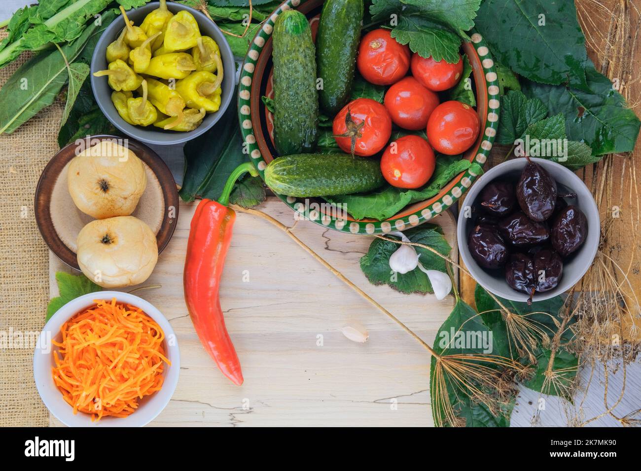 Verschiedene fermentierte pflanzliche Lebensmittel: Gurken, Tomaten, Äpfel, Pflaumen, Paprika und Karotten. Gesunde Ernährung in Schüsseln. Stockfoto