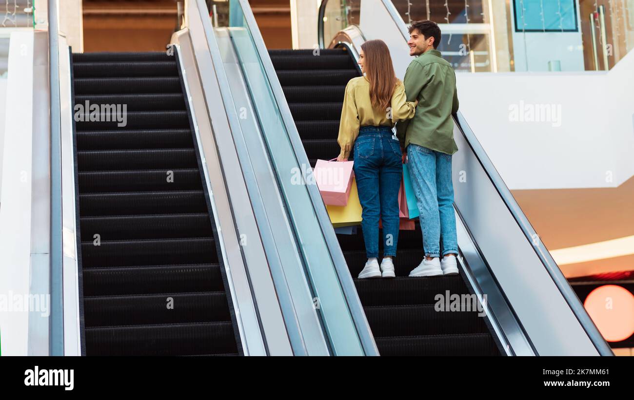 Käufer Paar Stehend Auf Beweglichen Treppen In Der Mall, Rückansicht Stockfoto