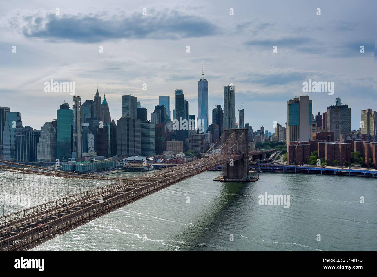 Sehen Sie Manhattan entlang des East River über die malerische Brooklyn Bridge in New York City, den Vereinigten Staaten von Amerika. Stockfoto