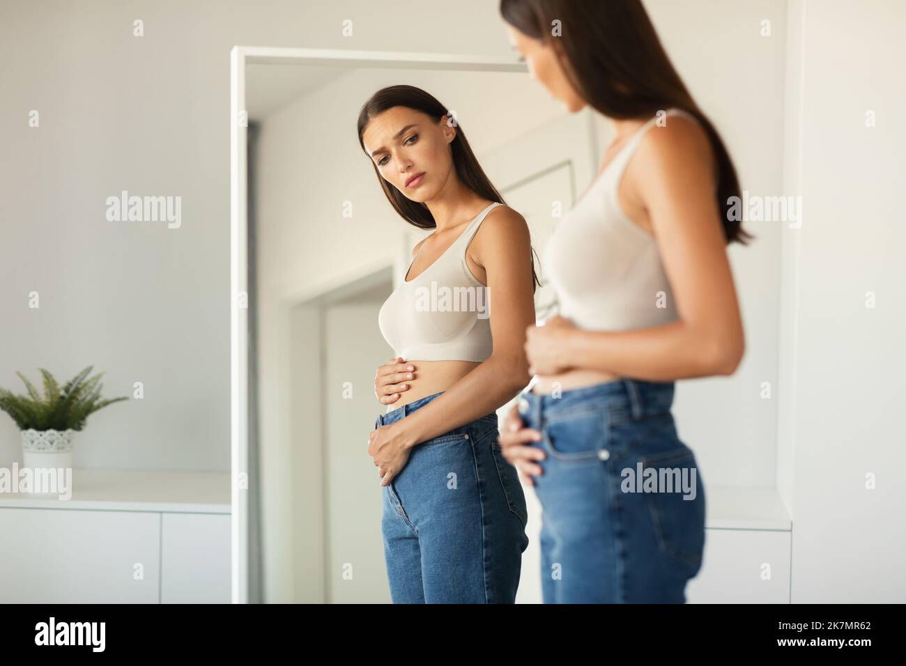 Unglückliche Dame, Die Den Flachen Bauch Berührt Und Zu Hause Magenschmerzen Hat Stockfoto