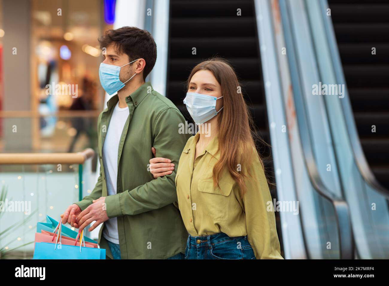 Ehepartner Einkaufen Wandern Mit Taschen, Die Gesichtsmasken Tragen, In Der Mall Stockfoto