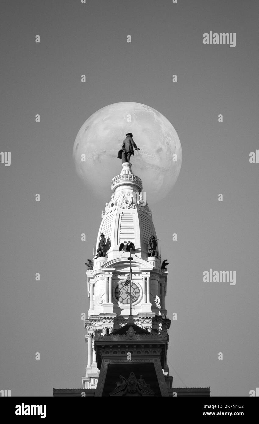 Der weiße Vollmond, der hinter der William Penn-Statue auf dem Rathaus von Philadelphia in Philadelphia, Pennsylvania, zu sehen ist Stockfoto