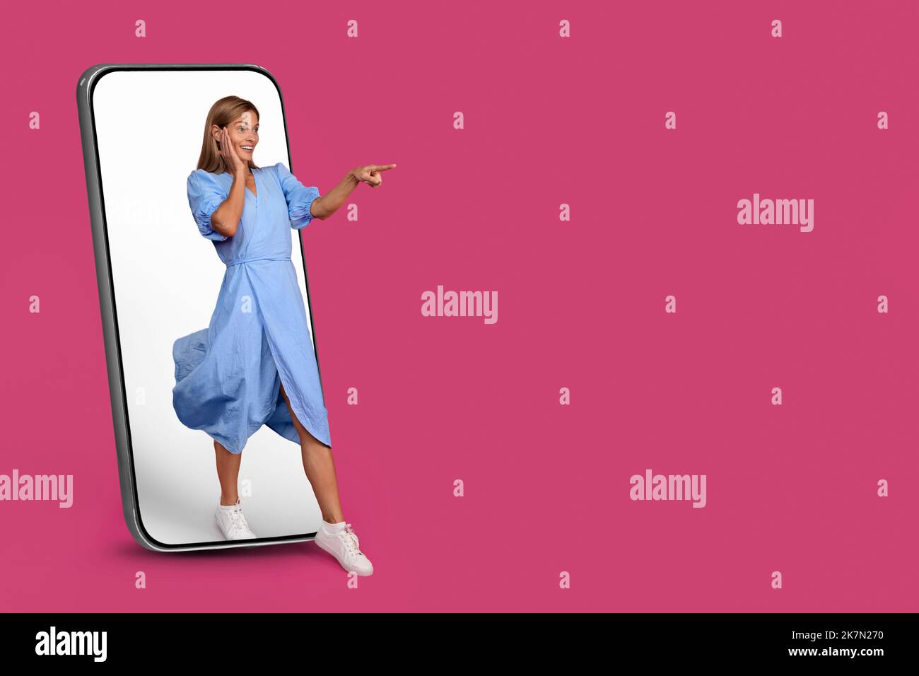 Schockiert froh reifen europäischen weiblich kommt aus großen Smartphone mit leerem Bildschirm, zeigt Finger auf leeren Raum Stockfoto