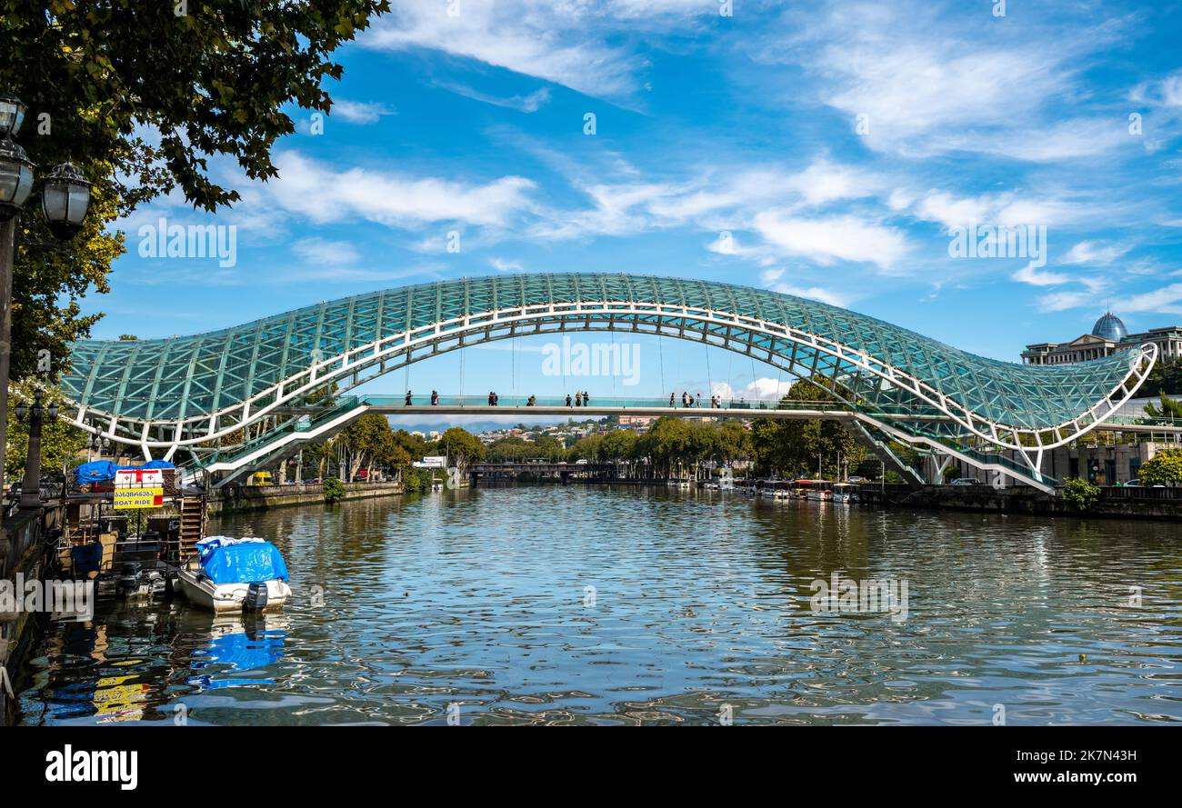 Die Friedensbrücke ist eine bogenförmige Fußgängerbrücke, eine Stahl- und Glaskonstruktion, die den Fluss Kura in Tiflis überquert Stockfoto