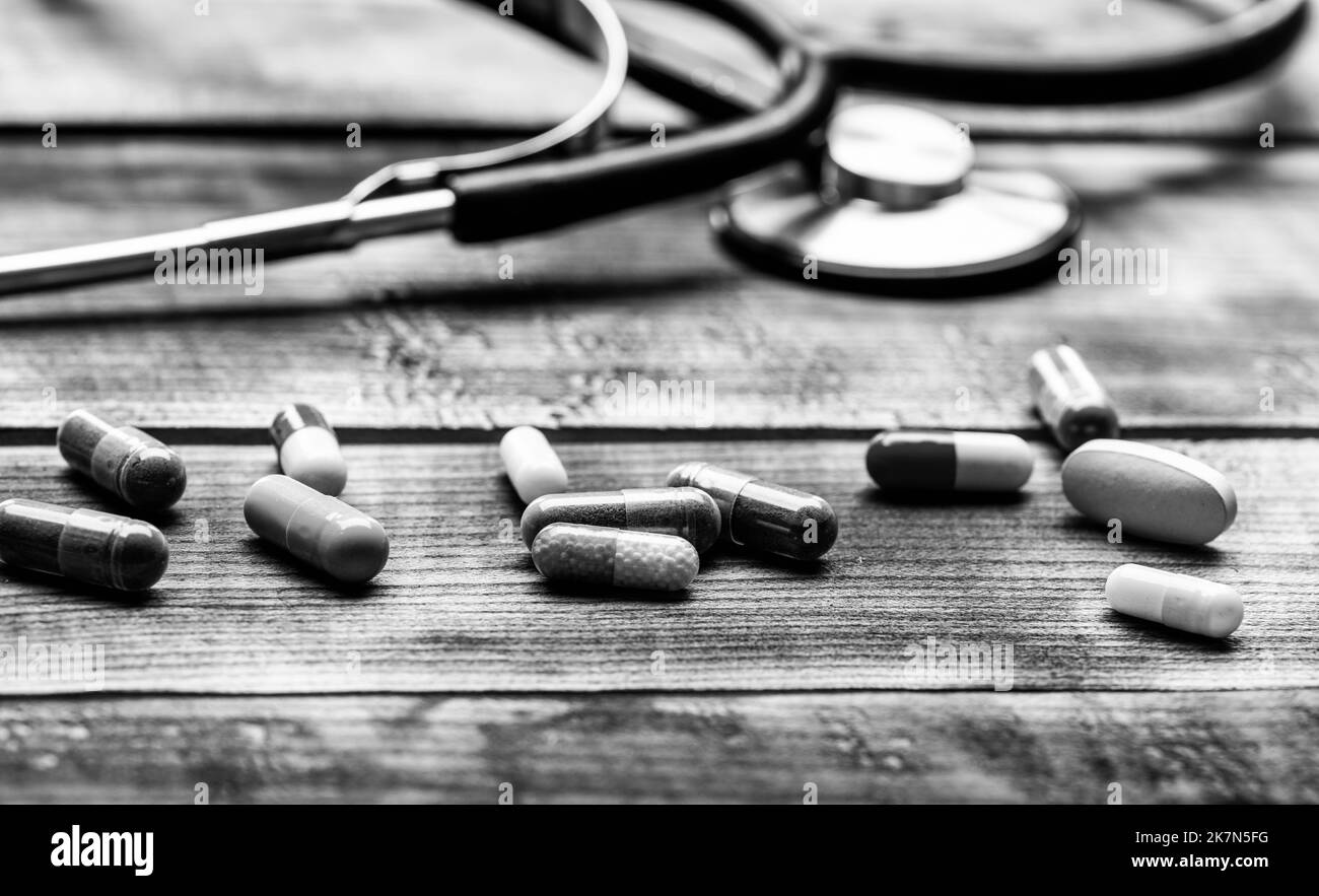 Verschiedene Kapseln pharmazeutische Medikamente und Stethoskop hölzernen Hintergrund, medizinische Versorgung Stockfoto