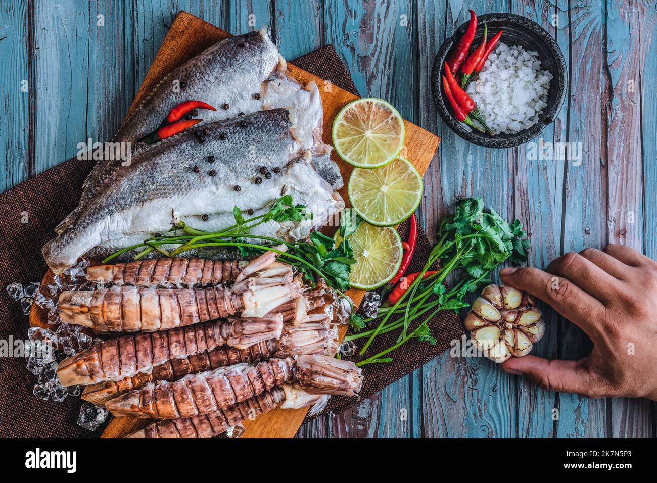 Ein Blick von oben auf rohen frischen Fisch und Krabben, Limetten, Knoblauch, Paprika und Salz auf einem Tisch Stockfoto