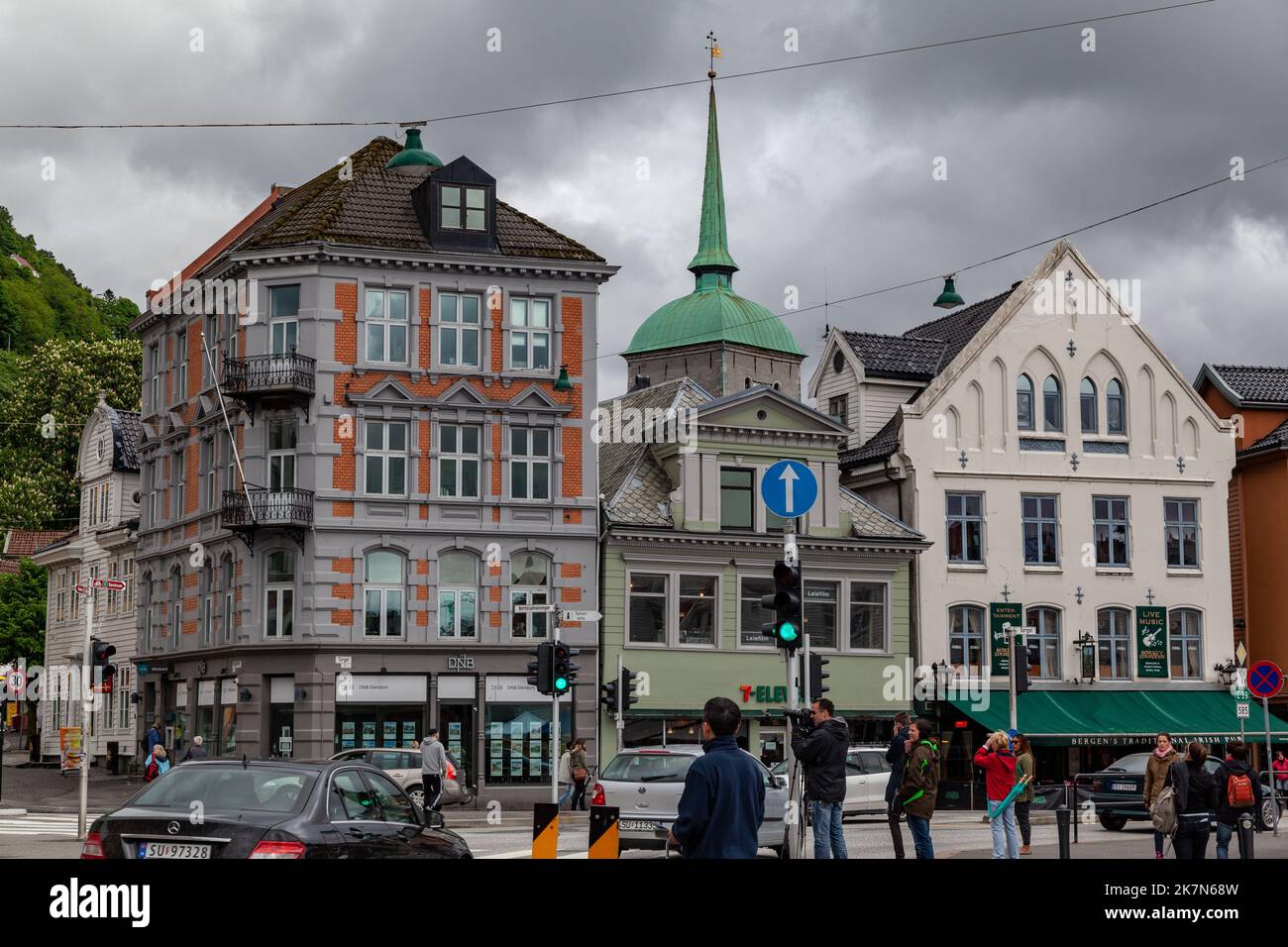 Historische Gebäude aus dem 19.. Jahrhundert an einer belebten Straße voller Verkehr und Menschen in Bergen, Norwegen Stockfoto