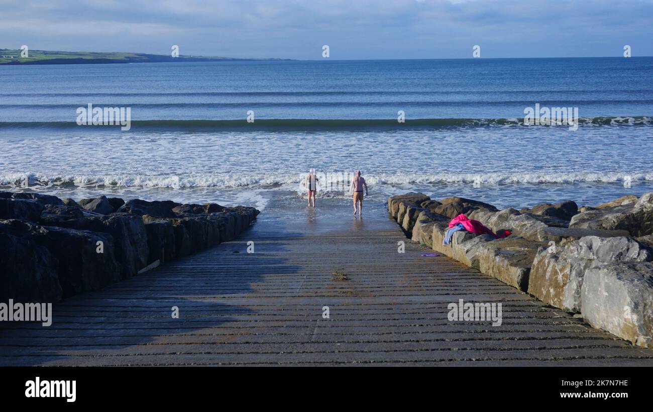 Zwei Badegäste tauchen im Oktober, dem Beginn der kalten Badesaison, in den Atlantik ein. Stockfoto