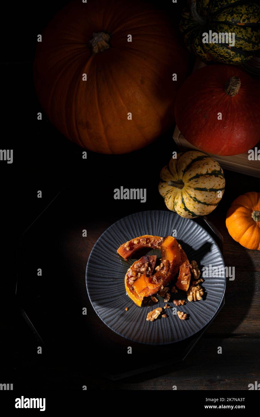 Dunkel launisch bildlich Stillleben von Herbst gerösteten Butternut Kürbis mit Zimt, Walnüssen und Honig bestäubt Stockfoto