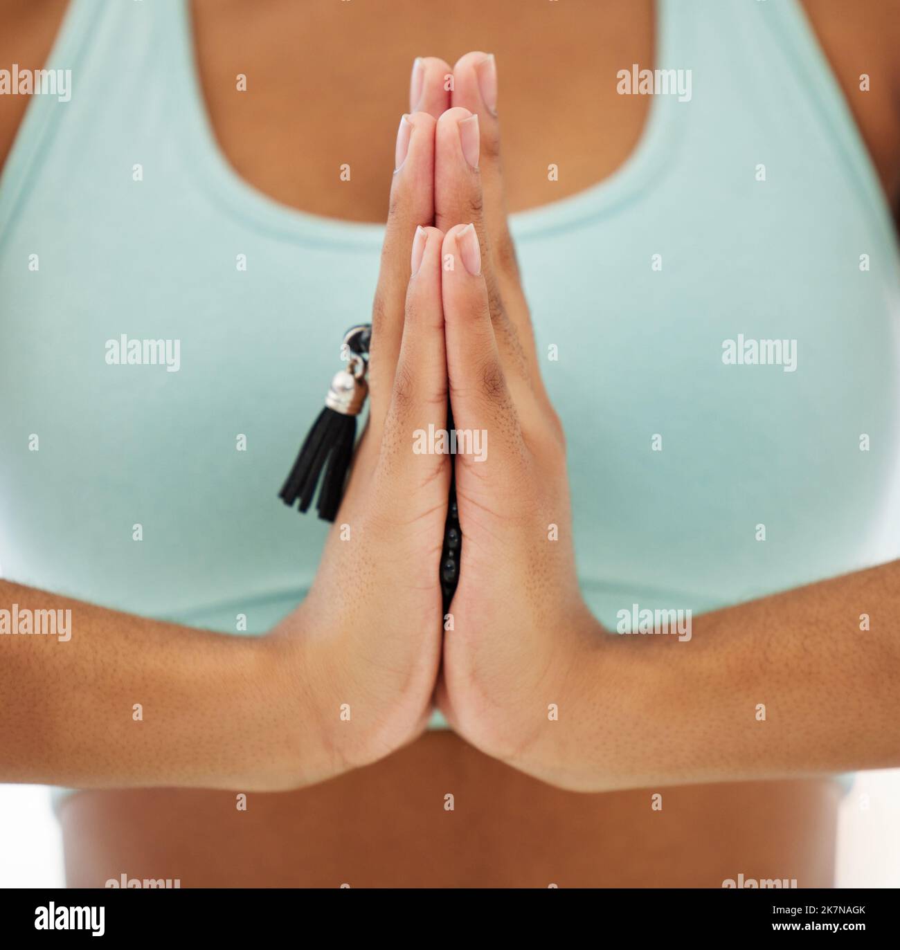 Konzentriert auf meine geistige Gesundheit. Eine unkenntliche Frau, die mala-Perlen hält und in einem Yoga-Studio meditiert. Stockfoto