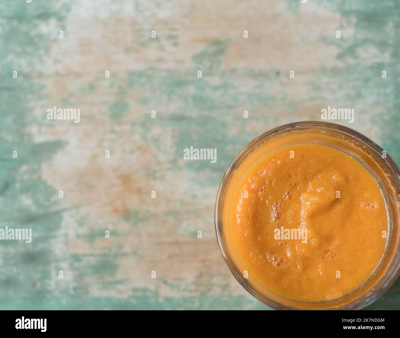 Trinkglas mit orangefarbenem Smoothie isoliert auf Holzhintergrund mit Kopierraum Stockfoto