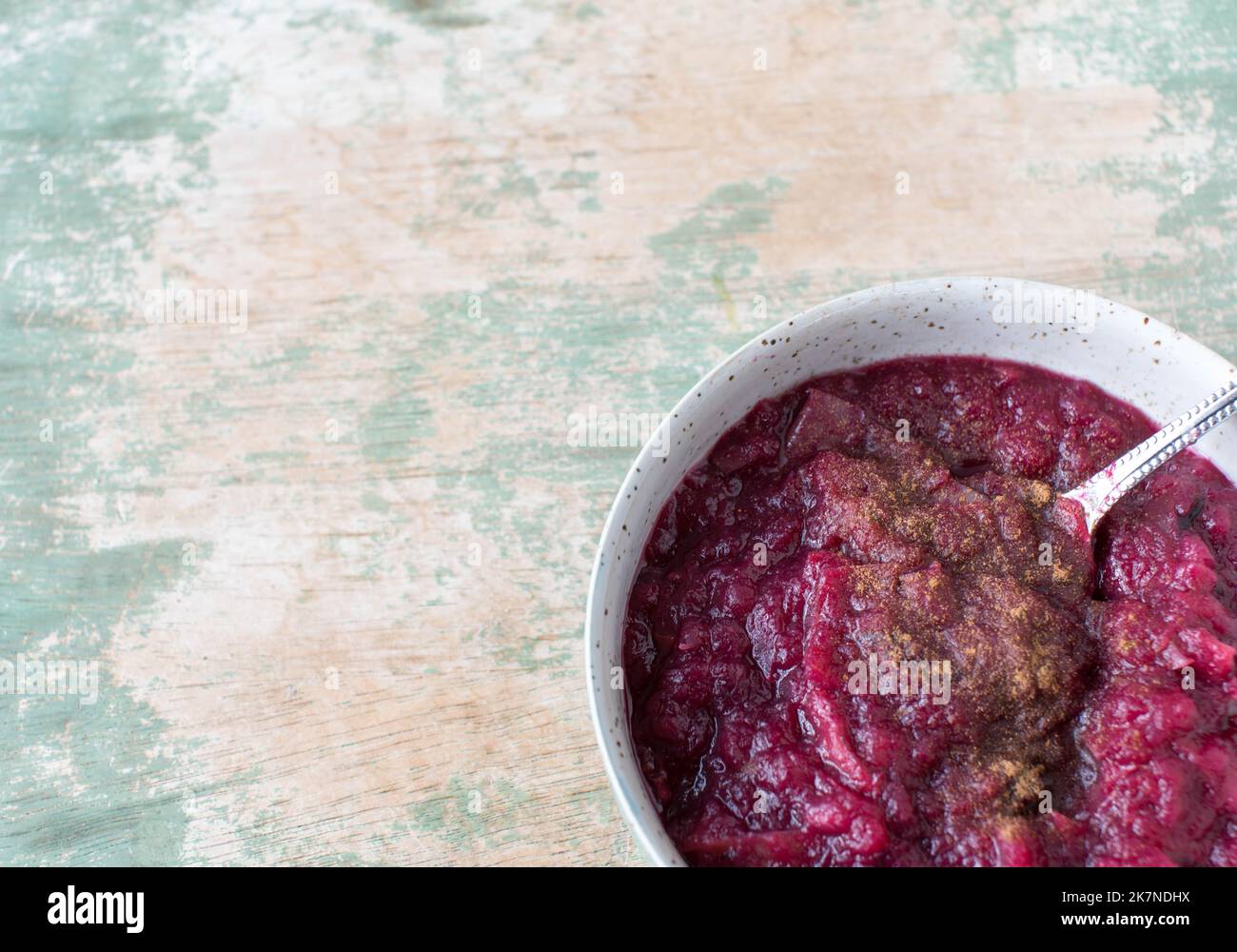 Gesundes Fruchtdessert mit geschmorten Äpfeln, Heidelbeeren und Zimt in einer Schale isoliert auf Holztisch mit Kopierraum Stockfoto