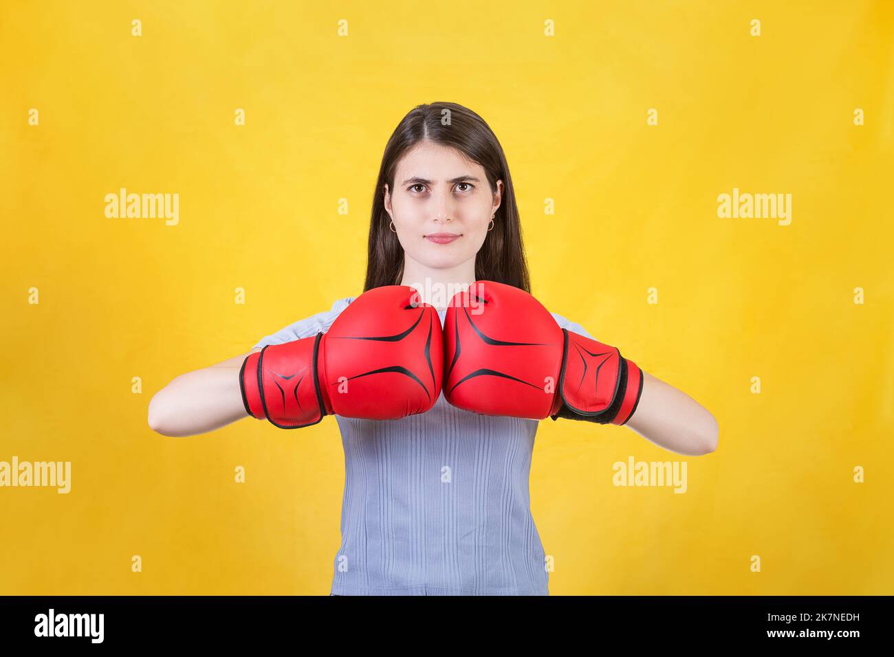 Die junge Frau mit roten Boxhandschuhen steht in einer kämpferischen Haltung bereit und schlägt ihre Fäuste. Portrait des entschlossenen Mädchens, das für den Kampf isoliert auf vorbereitet ist Stockfoto
