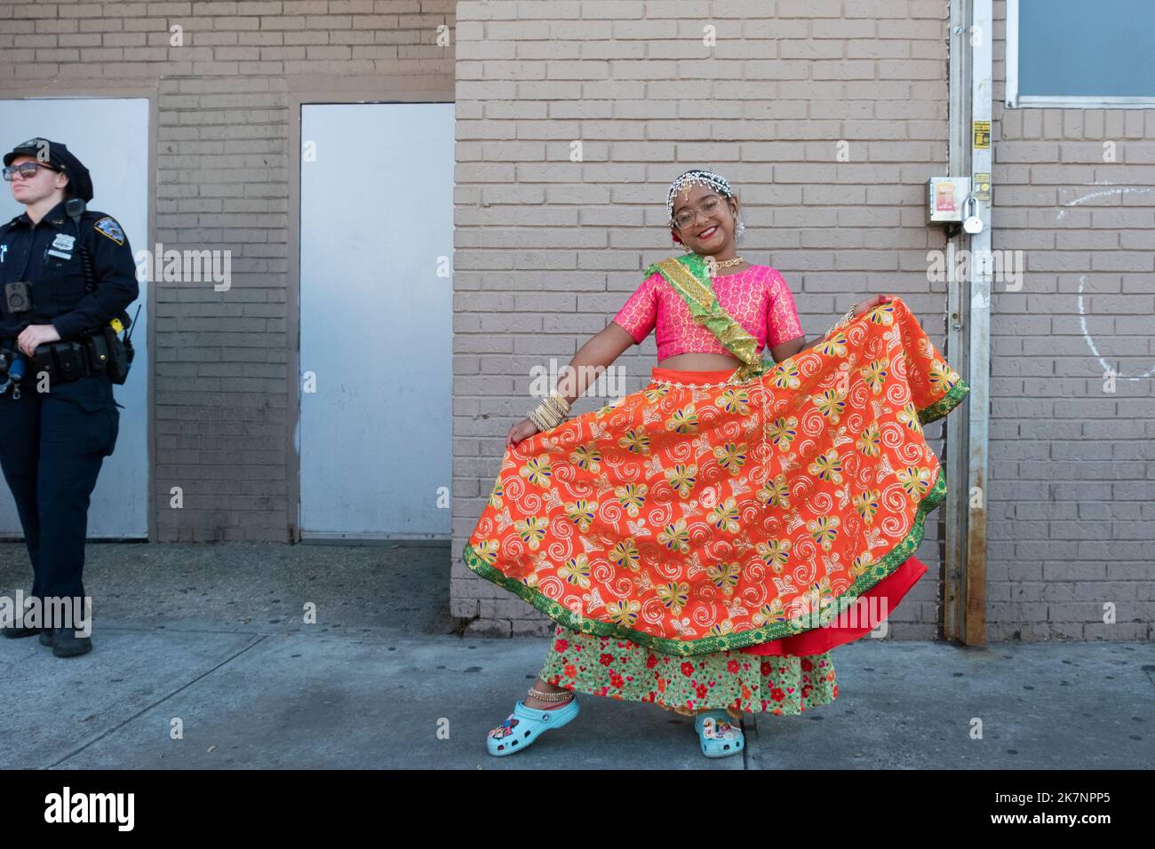 Ein junger süßer lächelnder Hindu-Teenager, der als Göttin Lakshmi gekleidet ist, bricht eine Tanzbewegung im Diwali 2022 in Queens, New York. Stockfoto