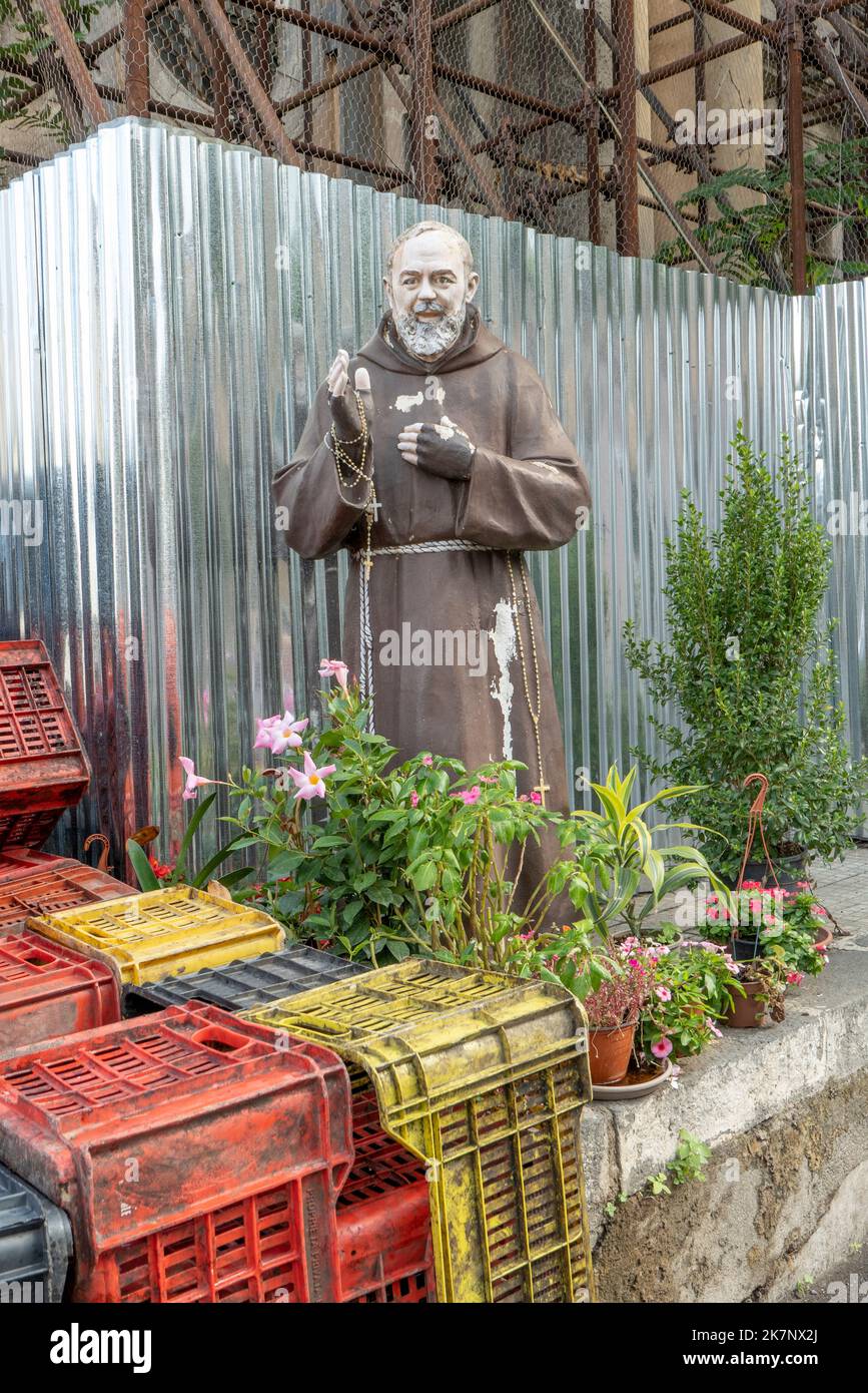 Sizilien, Italien - 26. September 2022: Statue von Padre Pio auf Sizilien auf einer Baustelle. Blumen und Flaschenhalter vorne. Stockfoto