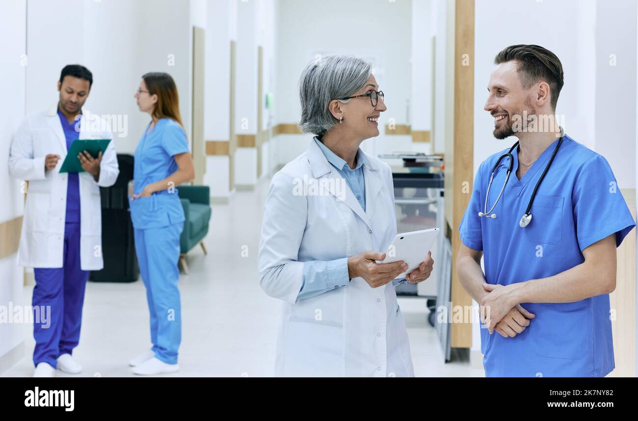 Ärzte im Gesundheitswesen machen Runden, reden im Krankenhauskorridor während der Arbeit. Krankenhausbehandlung Stockfoto