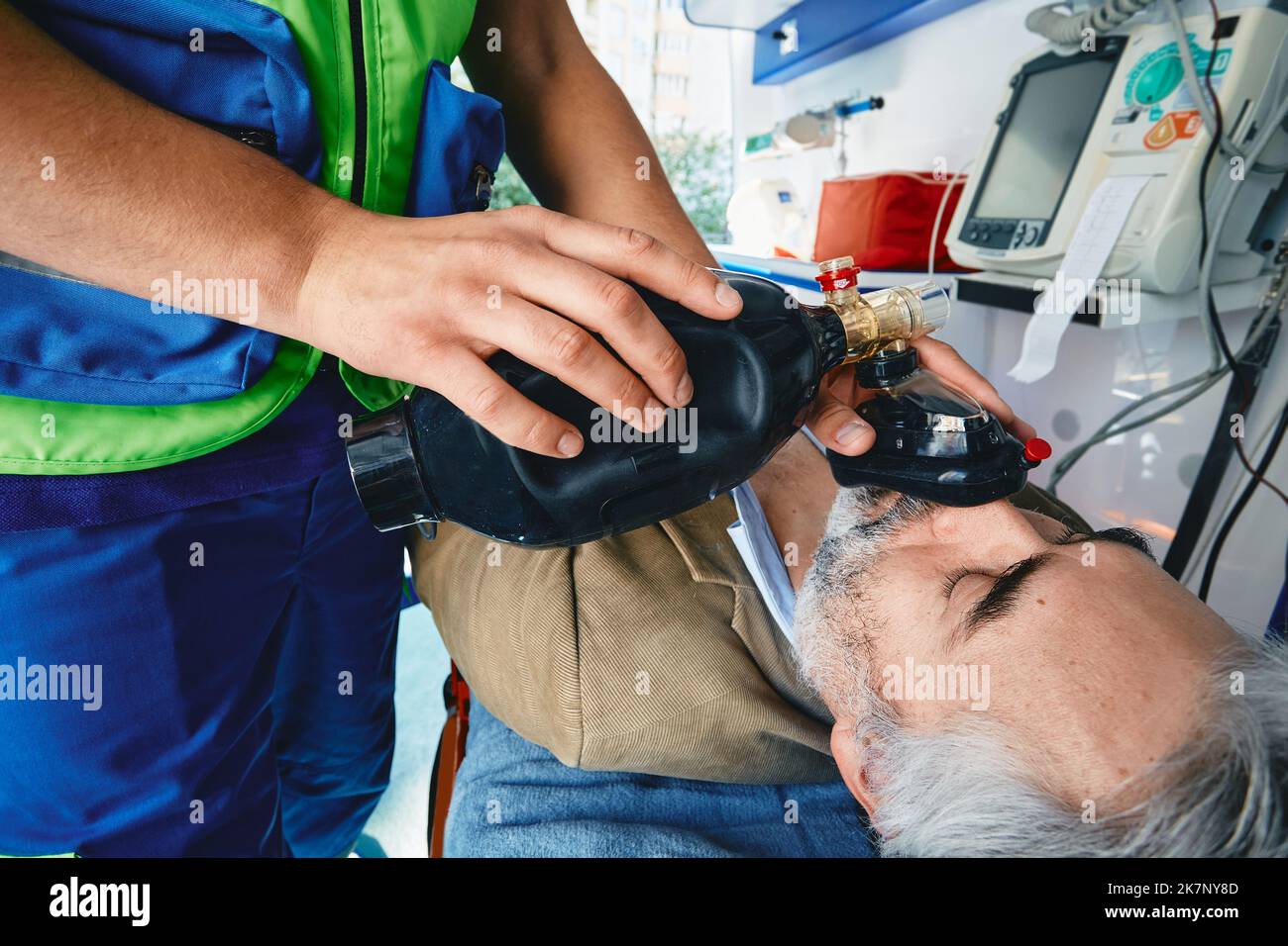 Notarzt führt künstliche Beatmung der Lunge und HLW an bewusstlosen männlichen Patienten mit manueller Beatmung im Krankenwagen durch. EMT, zuerst Stockfoto