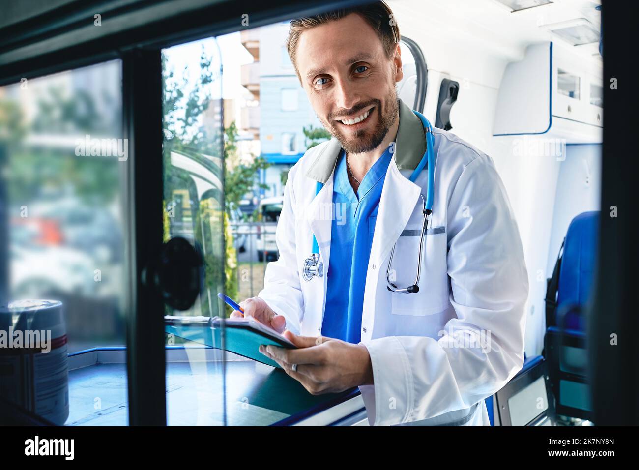 Freundlicher Arzt, der die Krankenakte des Patienten im Krankenwagen überprüft. Rettungsdienste Stockfoto