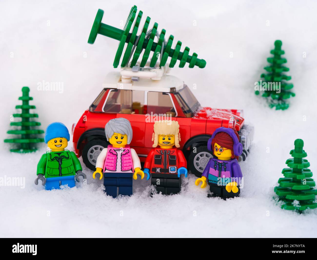 Tambow, Russische Föderation - 19. Januar 2022 Familie Lego steht vor einem roten Auto, auf dem der Weihnachtsbaum im Schnee steht. Stockfoto