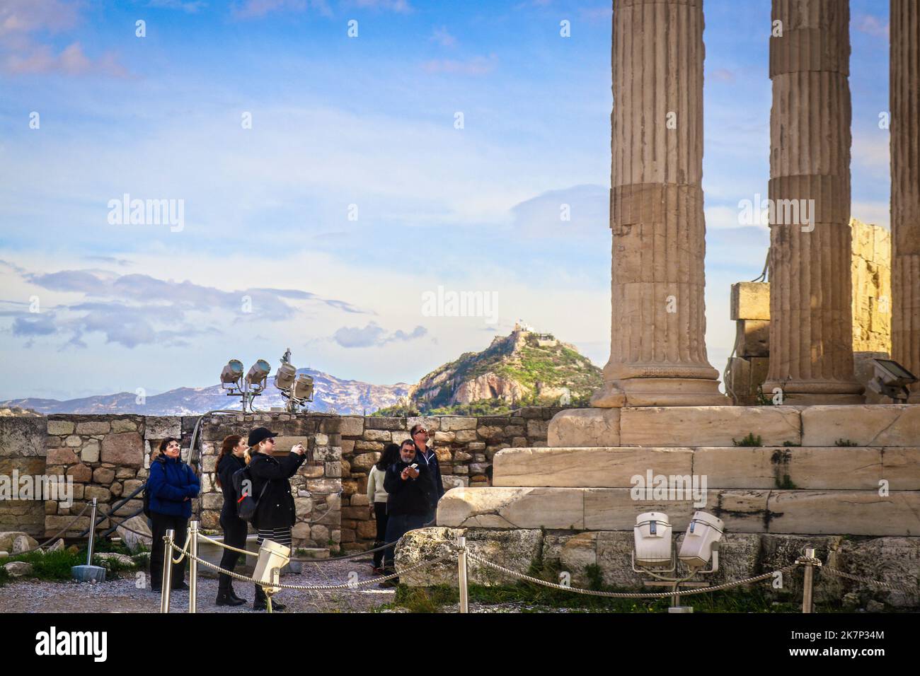 2018 01 03 Athen Griechenland - Touristen auf Akropolis fotografieren Ruinen mit dem Hügel Lycabethus und der Kirche des Agios Georgios, die im Hintergrund sichtbar ist R Stockfoto
