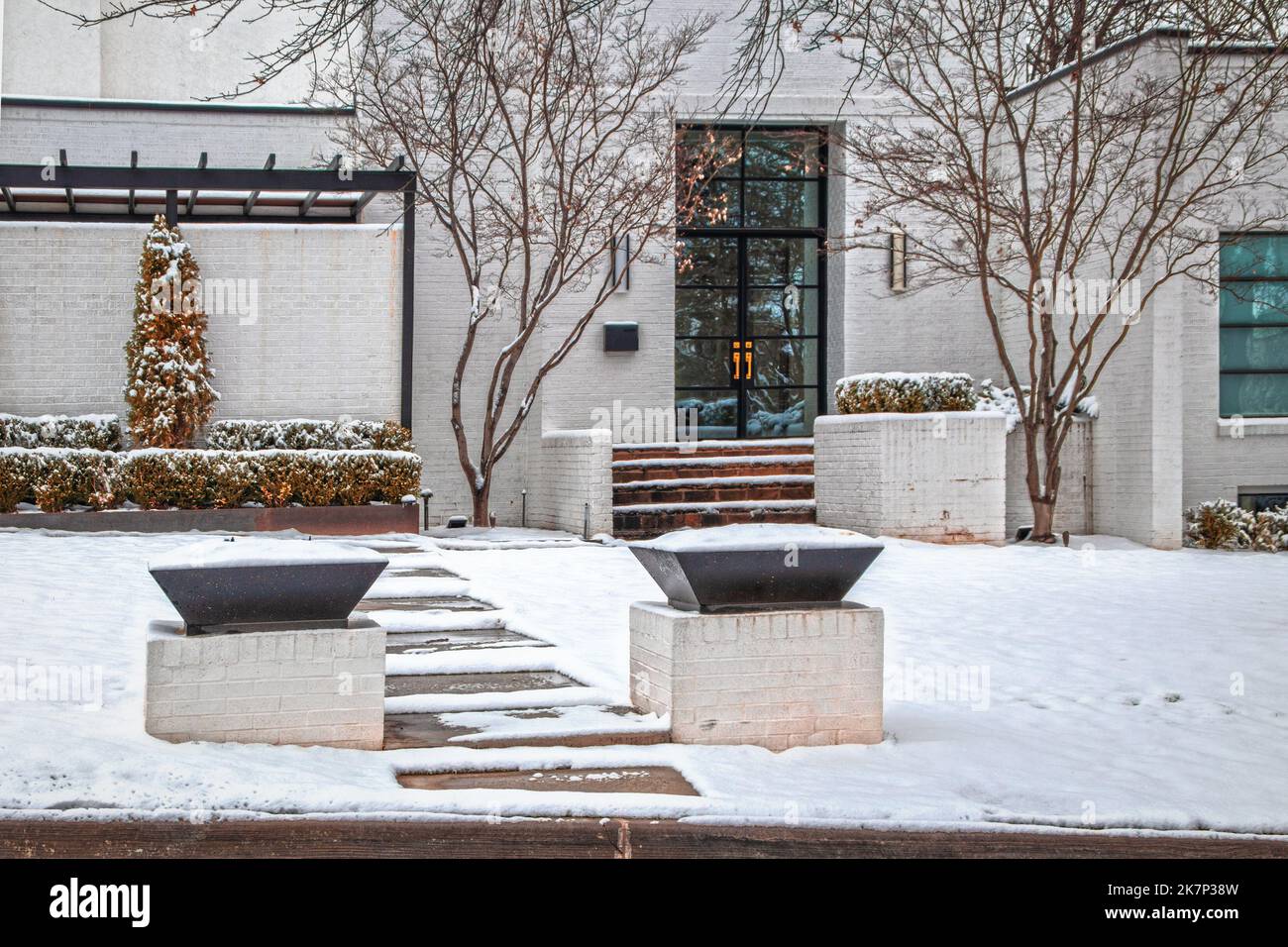 Eingang zu attraktiven weißen Backstein modernen Haus im Schnee mit Glastüren und Wand zum Terrassenbereich - vordere Stufen und leere Blumenkästen Stockfoto