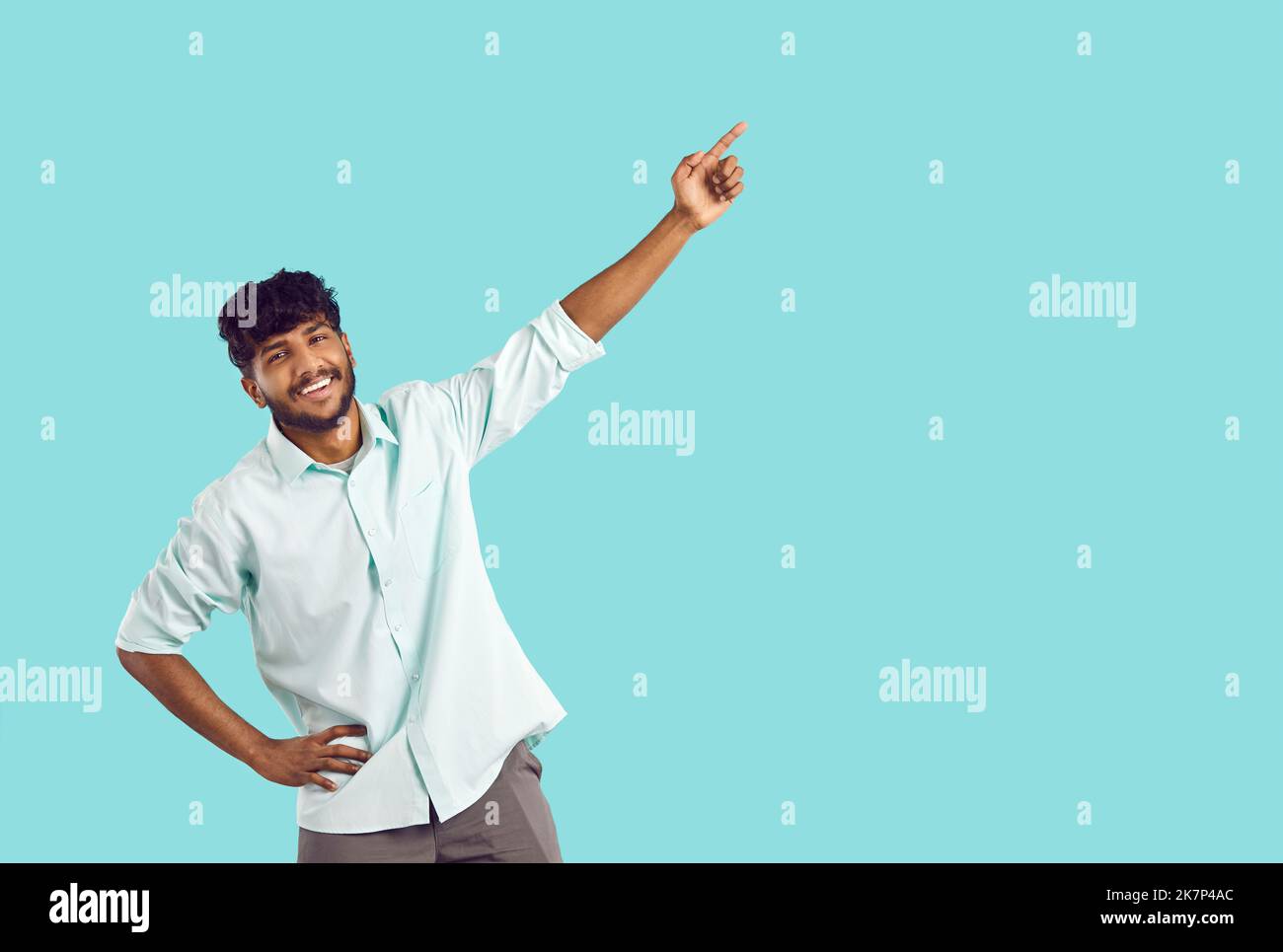 Happy indian Kerl zeigt auf Werbe-Text oder Ihr Geschäft Logo isoliert auf hellblauem Hintergrund. Stockfoto