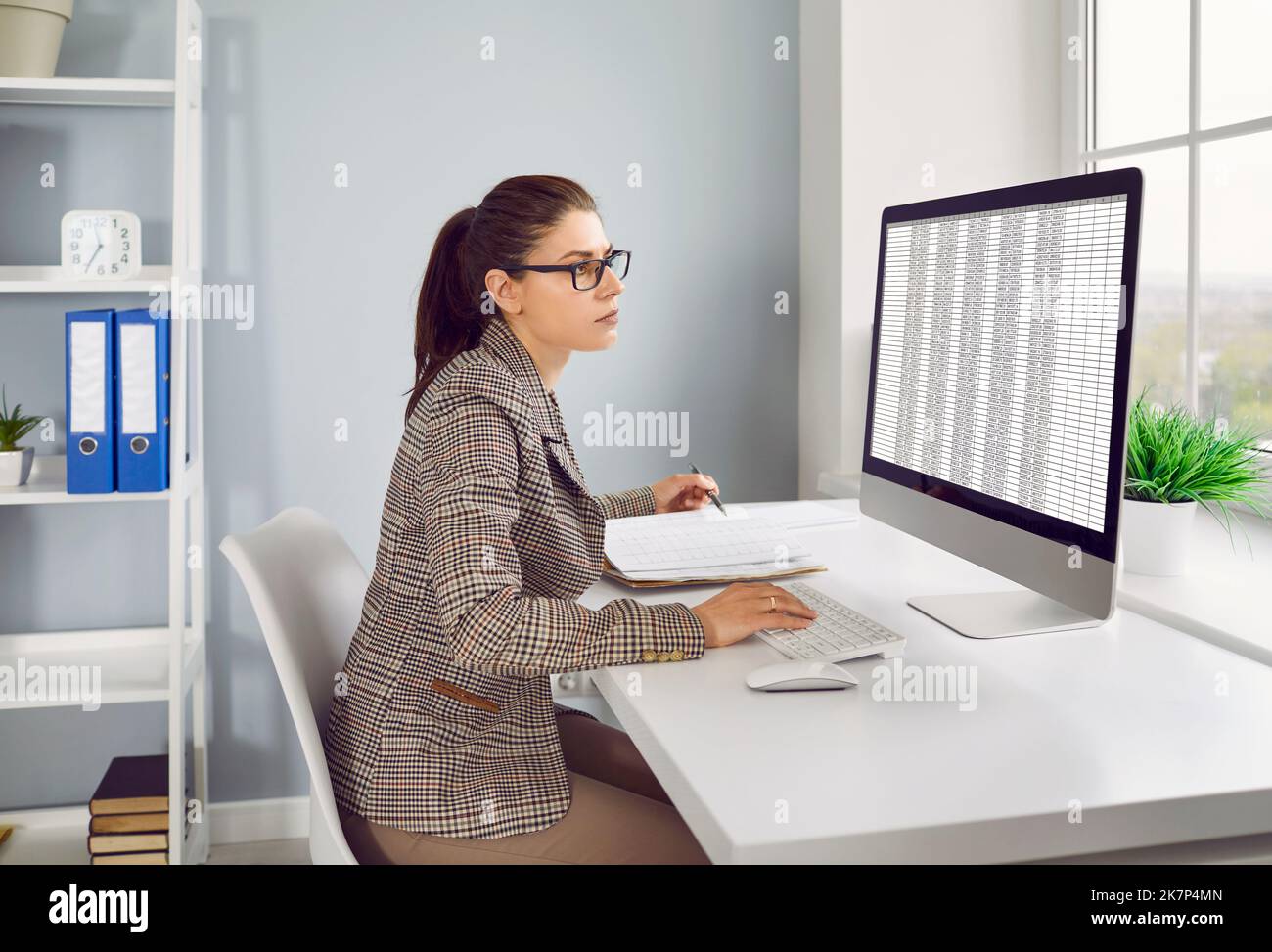 Finanzbuchhalter, der mit Geschäftstabellen auf einem Desktop-Computer im Büro arbeitet Stockfoto