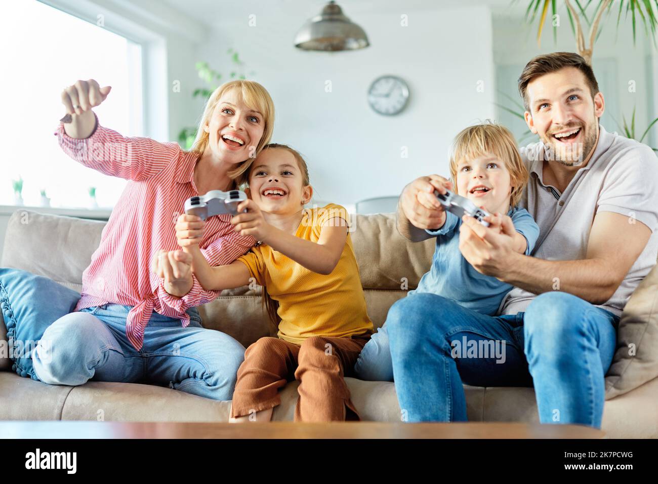 Kind Sohn Tochter Vater Mutter Familie glücklich spielen Konsole Kind Kindheit Joystick cotroller junge Mädchen Spaß zusammen Teamarbeit spielen Stockfoto