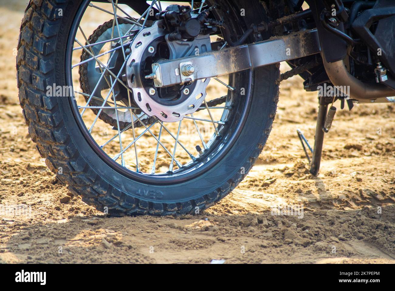 Aufnahme eines gerippten Hinterrades von Dirt Bike an der Startlinie des Rennens, das Schlamm wirft, während es sich bewegt und dabei die Bikes und Schutzgrear präsentiert Stockfoto