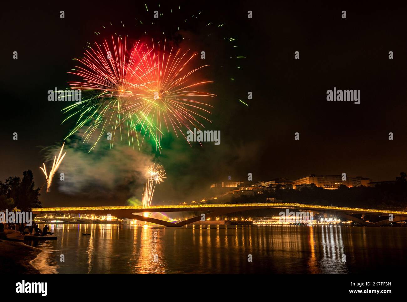 Nächtliches Feuerwerk bei den Feierlichkeiten in der Stadt Coimbra 2022 in Portugal mit dem Fluss Mondego und der Fußgängerbrücke Pedro e Inês Stockfoto