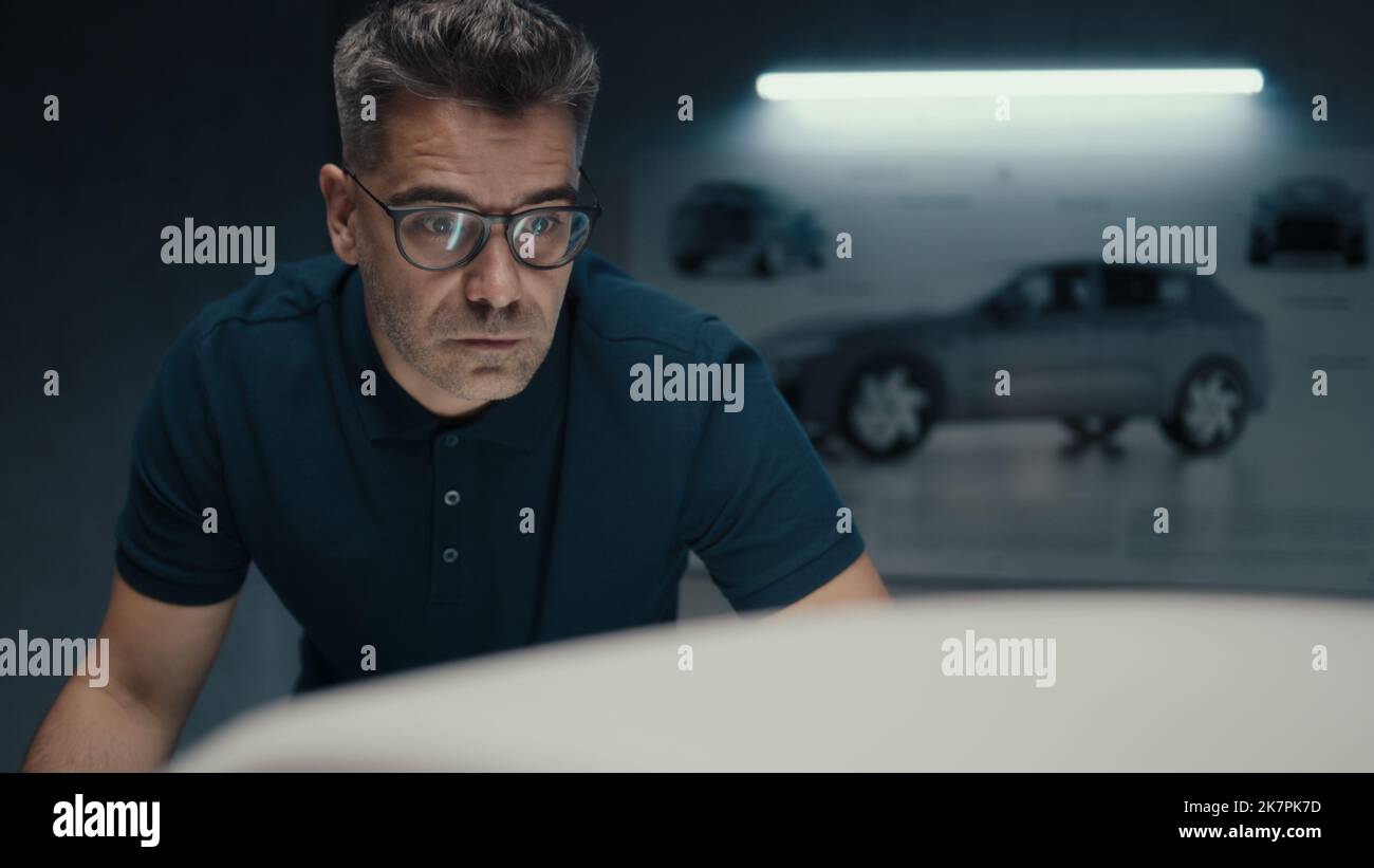 Der Automobilingenieur in einer schwarzen Brille diskutiert mit seinem Kollegen in einem Hightech-Automobilhersteller über das Design und die Veränderungen in der Skulptur eines Autos. Stockfoto