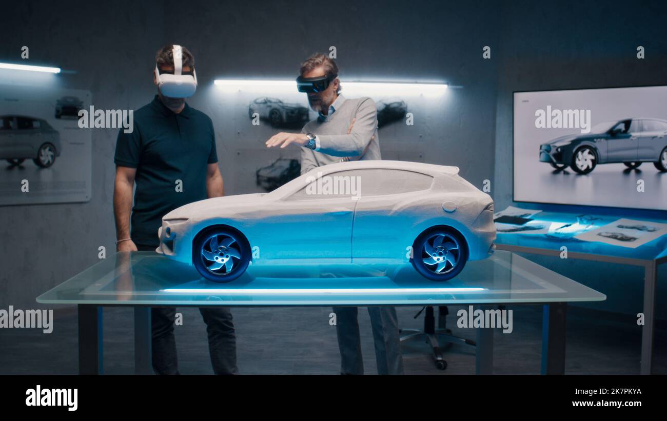 Professionelle Automobilingenieure mit VR-Headset und Joysticks sprechen über die Fahrzeugproduktion, während sie in einem Hightech-Büro vor einem prototypecar Modell stehen. Analyse und Verbesserung des Fahrzeugdesigns. Stockfoto