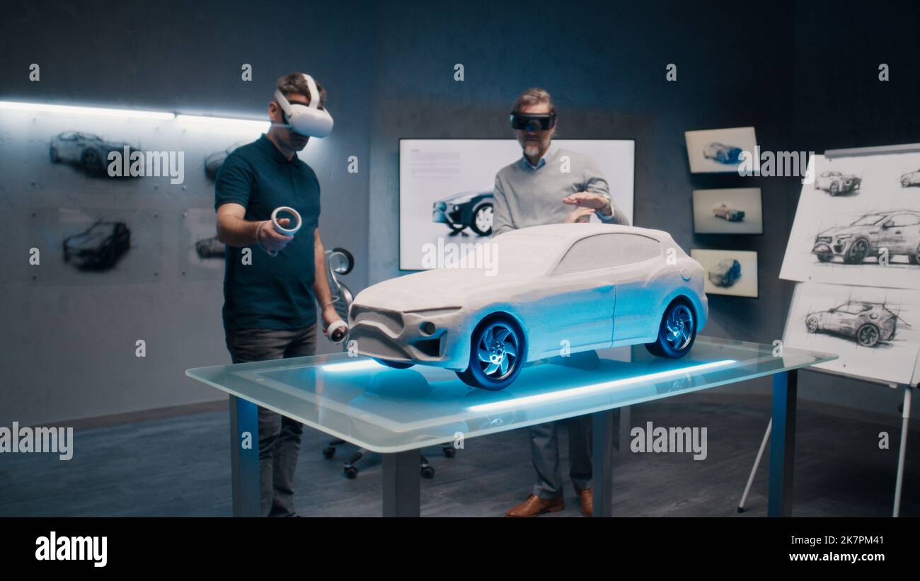 Professionelle Automobilingenieure mit VR-Headset und Joysticks sprechen über die Fahrzeugproduktion, während sie in einem Hightech-Büro vor einem prototypecar Modell stehen. Analyse und Verbesserung des Fahrzeugdesigns. Stockfoto