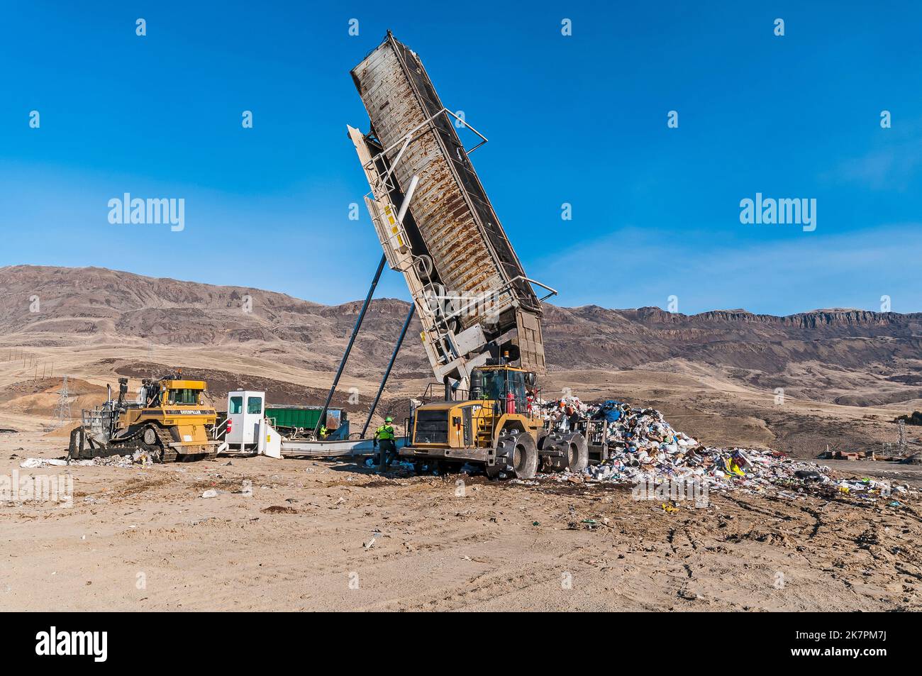 Ein Sattelkipper und die schwere Ausrüstung, die zum Verteilen und Zerkleinern von festen Abfällen in den Boden mit Bulldozern und Bodenverdichtern verwendet wird. Stockfoto